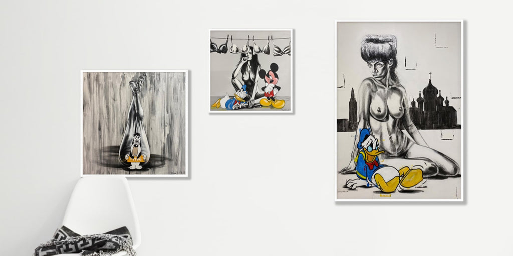 3 pieces of Frank De Decker nudes and toons collection in white frames on a blank wall